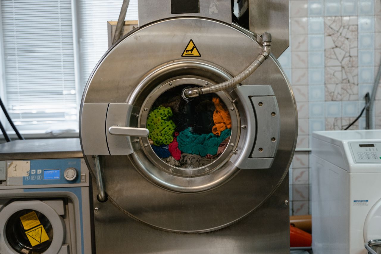 Lavatrice industriale in funzione, piena di capi colorati
