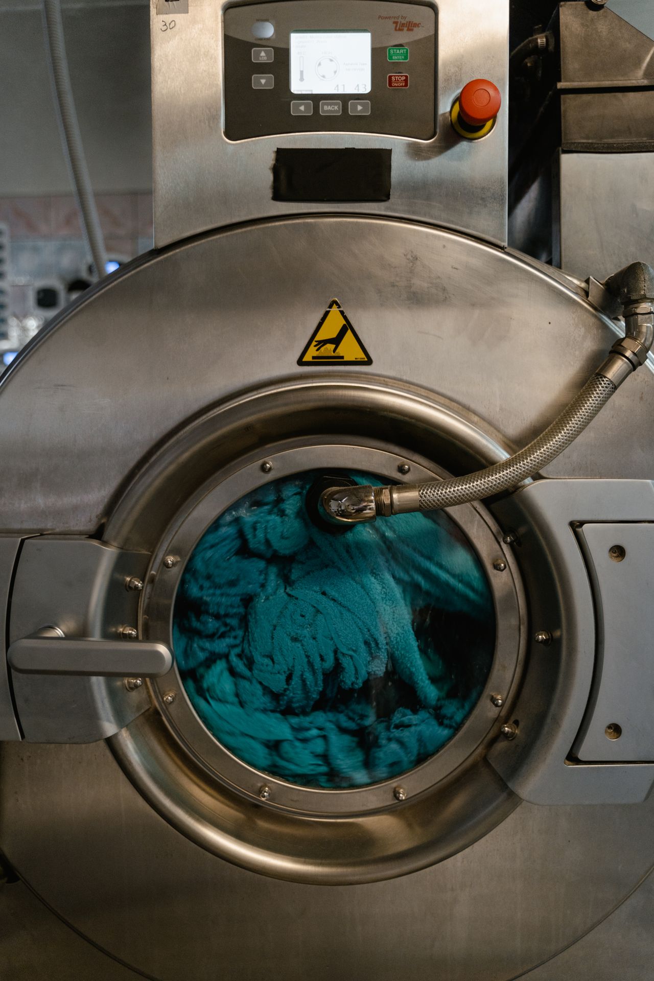 Lavatrice industriale piena di biancheria verde acqua